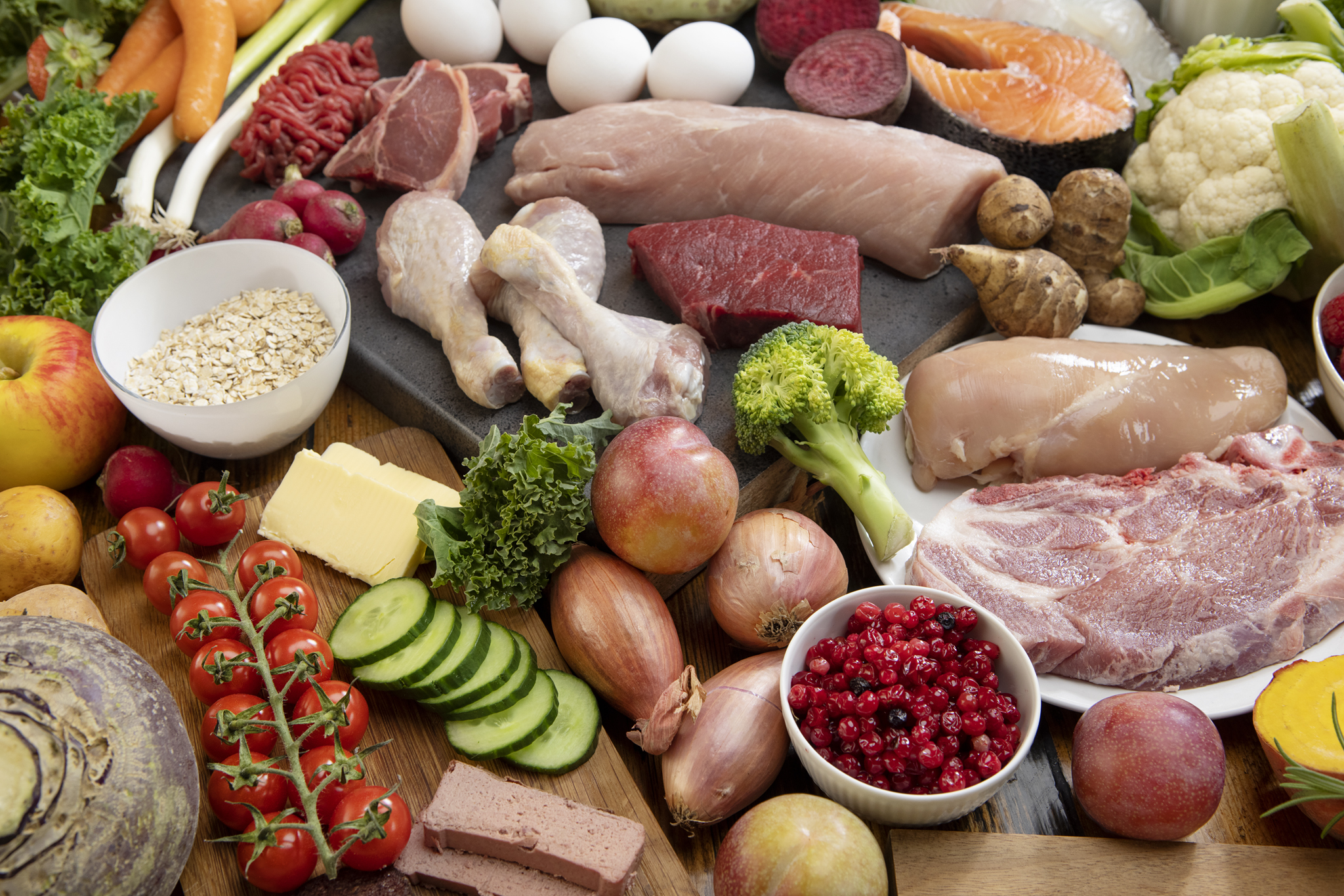 En rekke ulike matvarer på et bord, inkludert kjøtt, egg, grønnsaker og frukt.